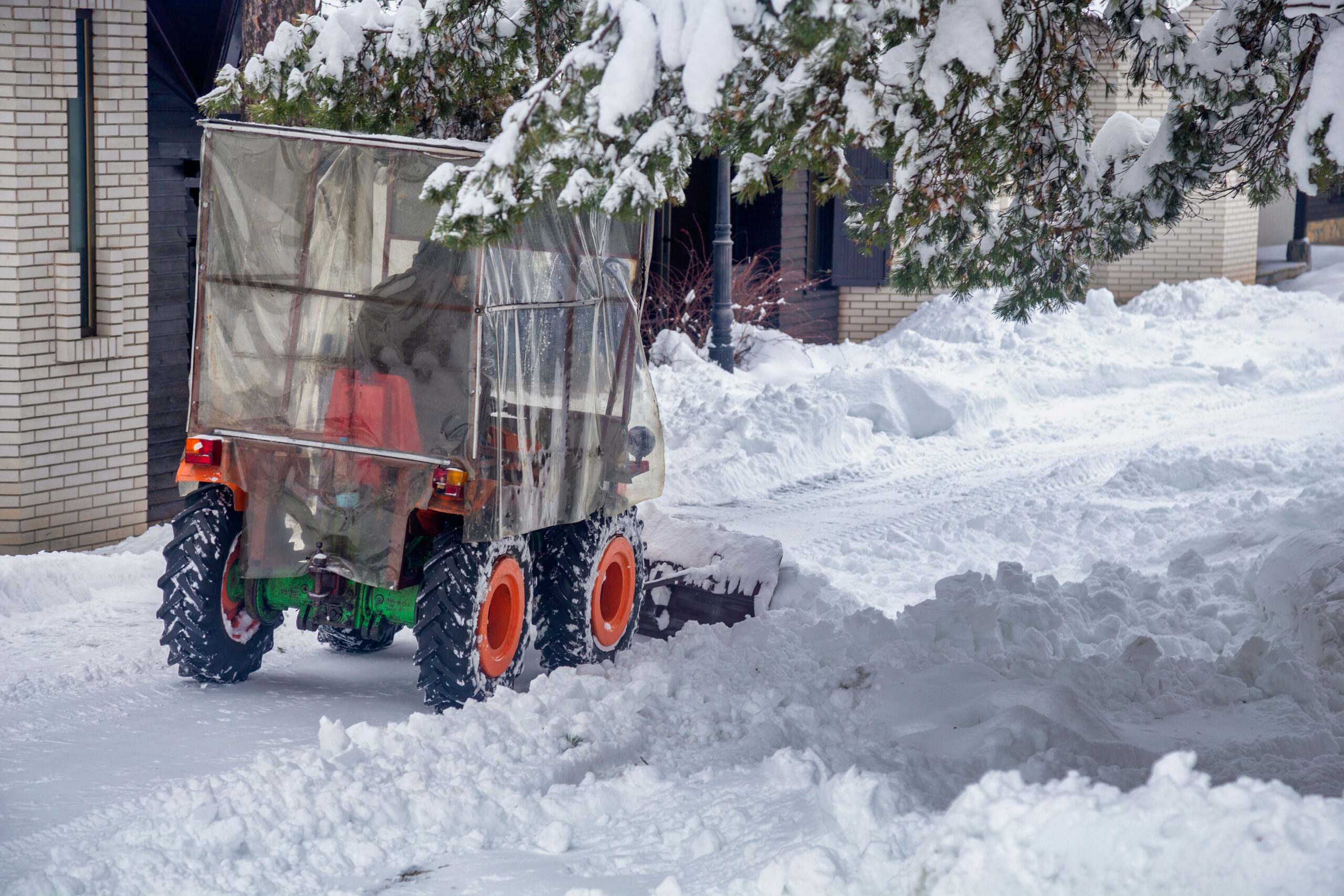Small utility vehicle removes snow from a residential driveway after fresh accumulation.